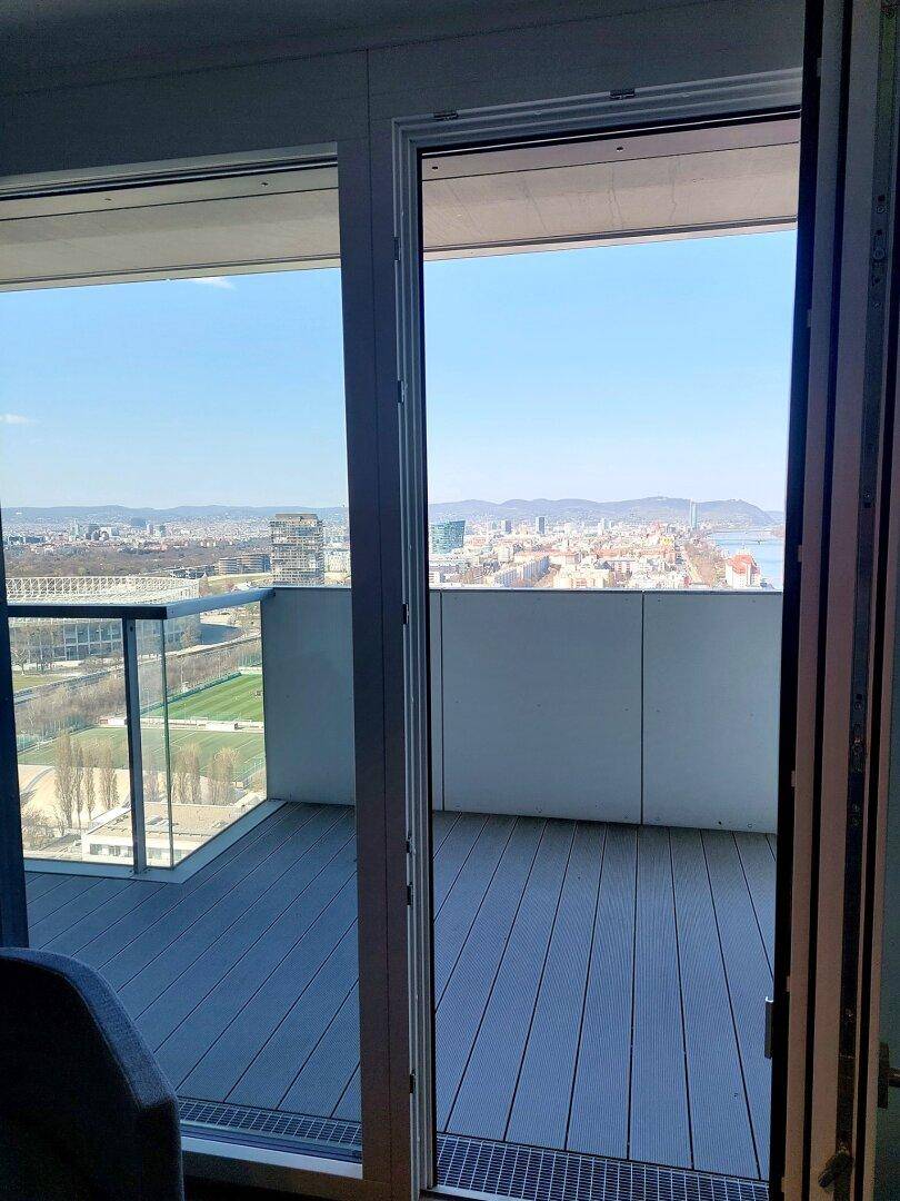 Weitblick aus dem Wohnbereich auf die Stadtlandschaft, den Fluss und die umliegenden Berge.