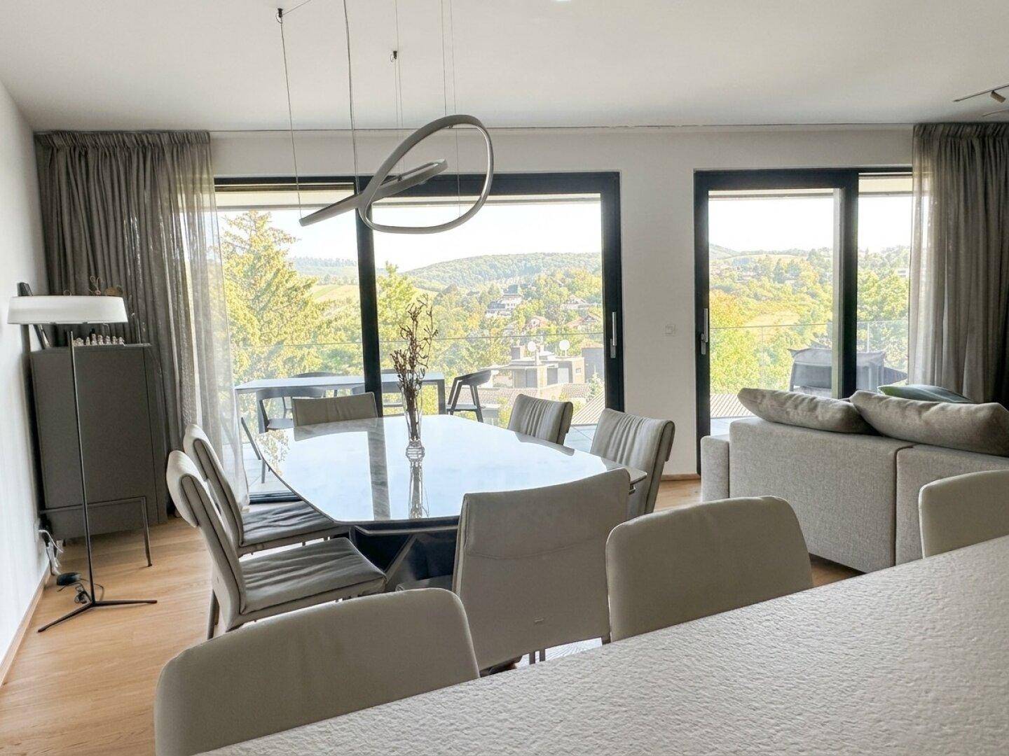 Eleganter Essbereich mit modernem Tisch und Stühlen, umgeben von großen Fenstern mit Aussicht.