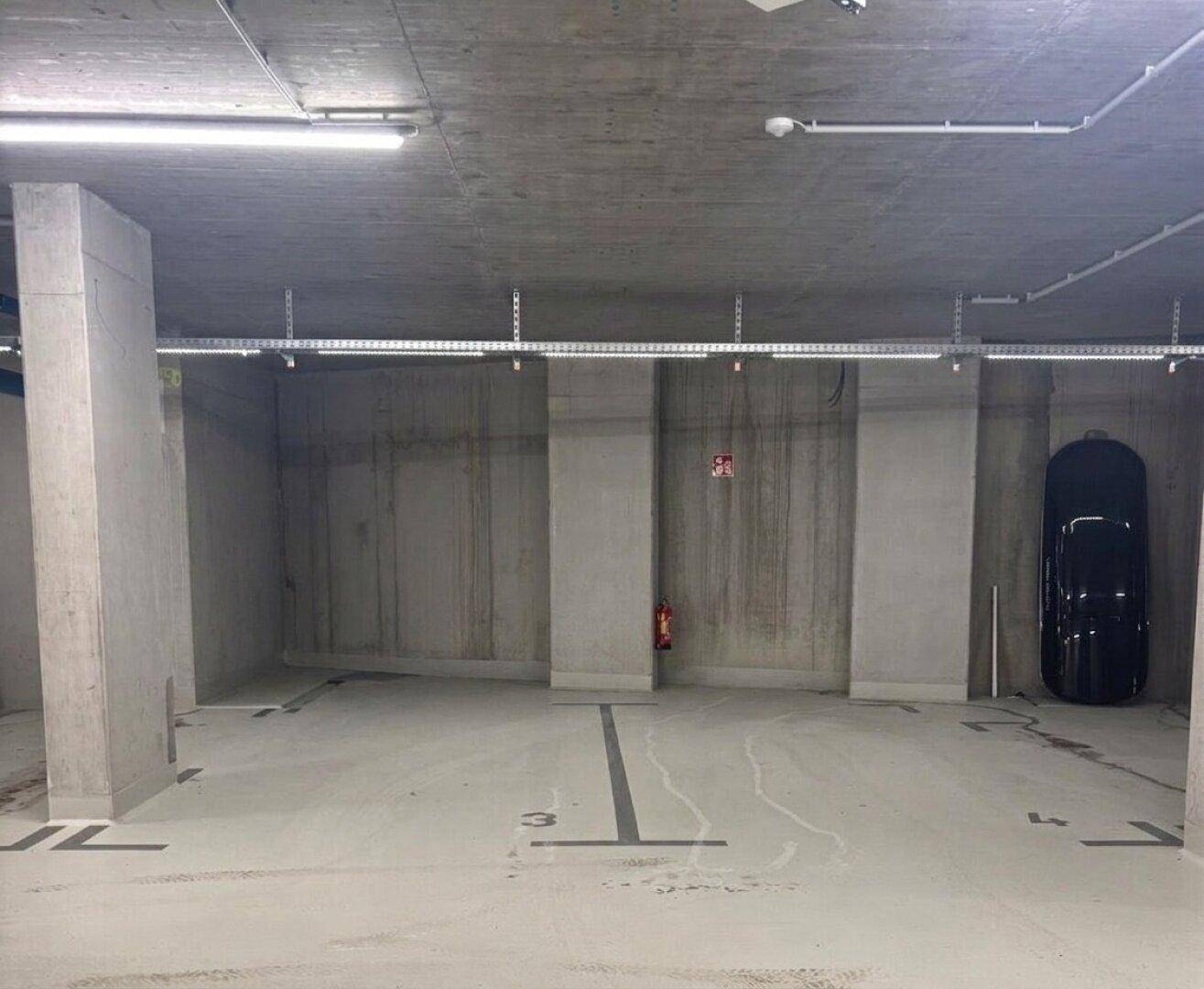 Breiter Stellplatz in einer modernen Tiefgarage mit Betonwänden und guter Beleuchtung.