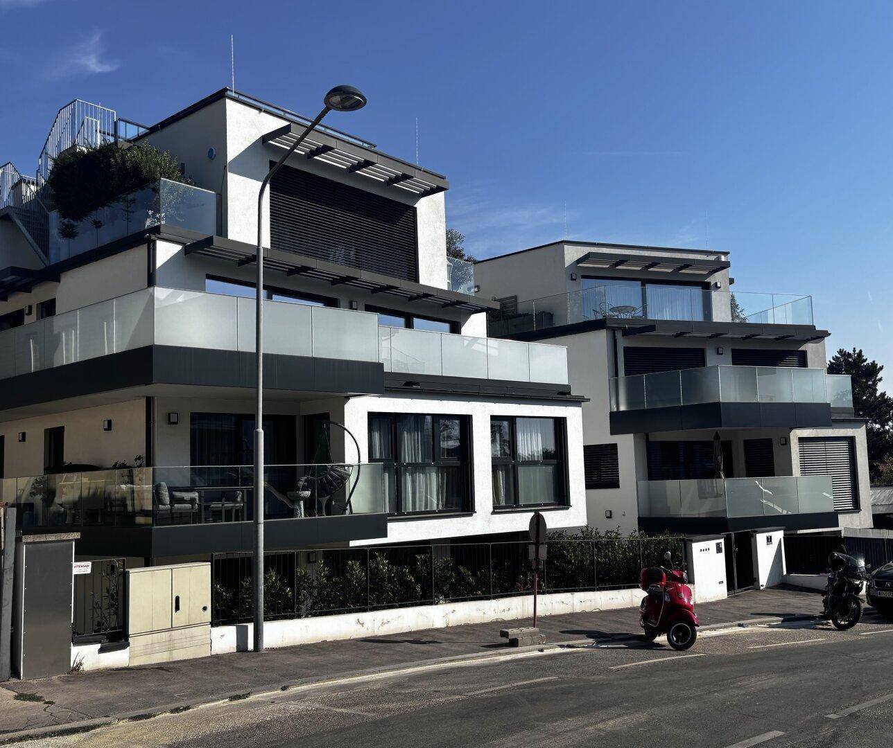 Ansicht eines modernen Apartmentgebäudes von der Straße mit mehreren Balkonen und stilvoller Fassade.