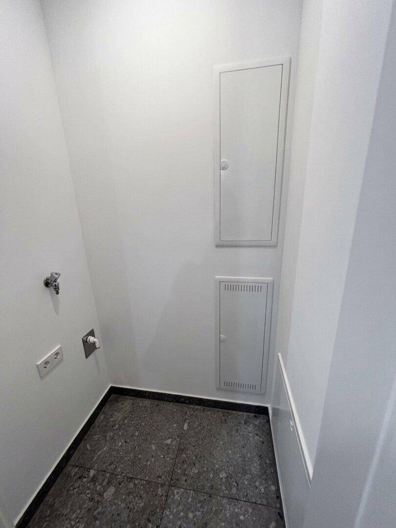 Kleiner Hauswirtschaftsraum mit Fliesenboden und Anschlüssen für Waschmaschine oder Trockner.