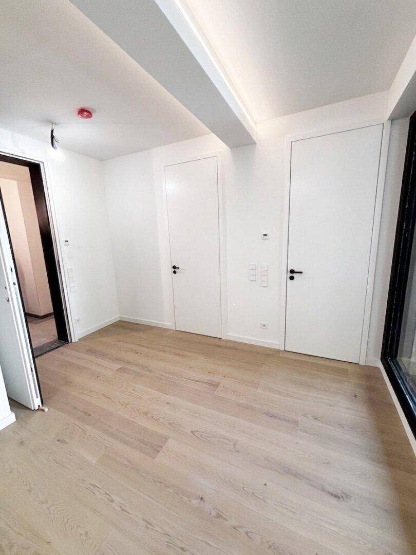 Heller Raum mit Holzboden und weißen Türen, bietet vielseitige Nutzungsmöglichkeiten.