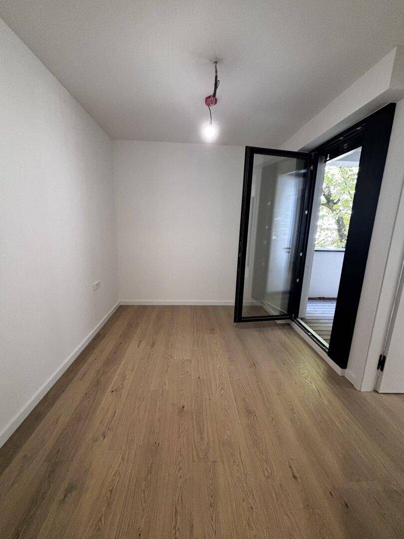 Heller Raum mit Holzboden und Zugang zu einem Außenbereich, ideal für frische Luft.