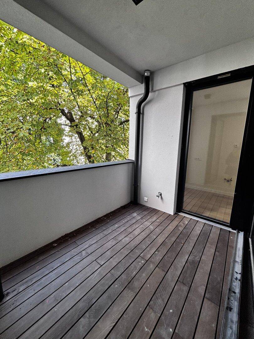 Balkon mit Holzdielen und Blick ins Grüne, ideal zum Entspannen im Freien.