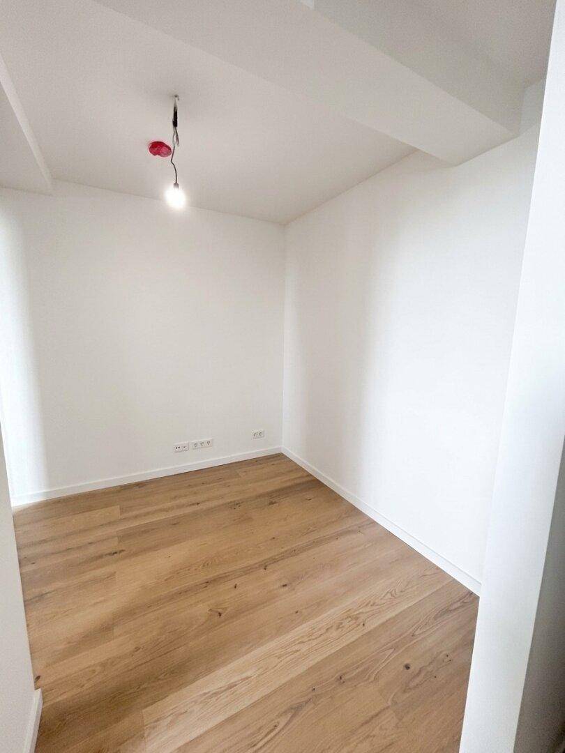 Leerer Raum mit hellem Holzboden und weißen Wänden, bereit zur individuellen Gestaltung.