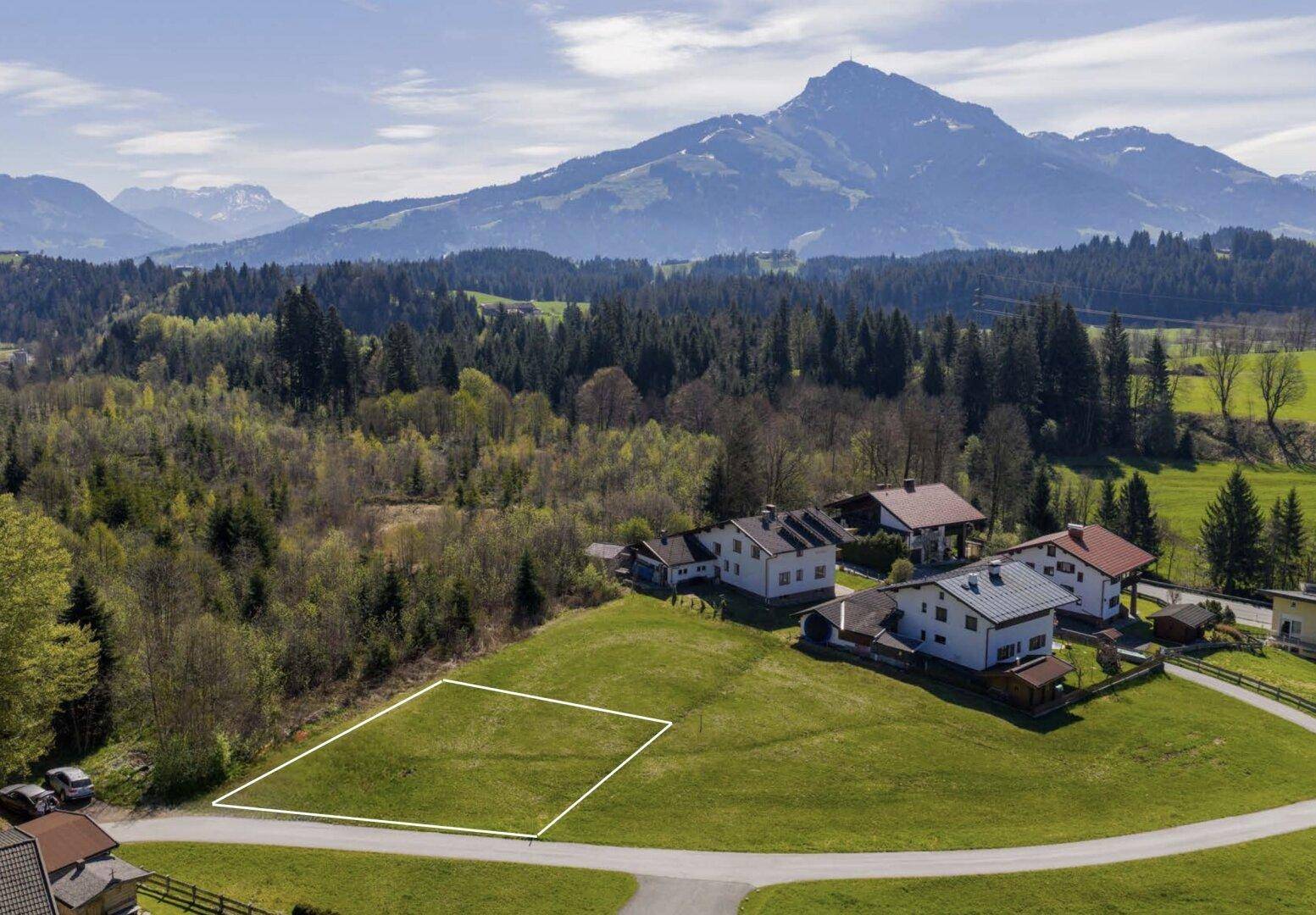 Baugrundstück in sonniger Hanglage mit weitem Blick auf die umliegende Berglandschaft und dichte Wälder.