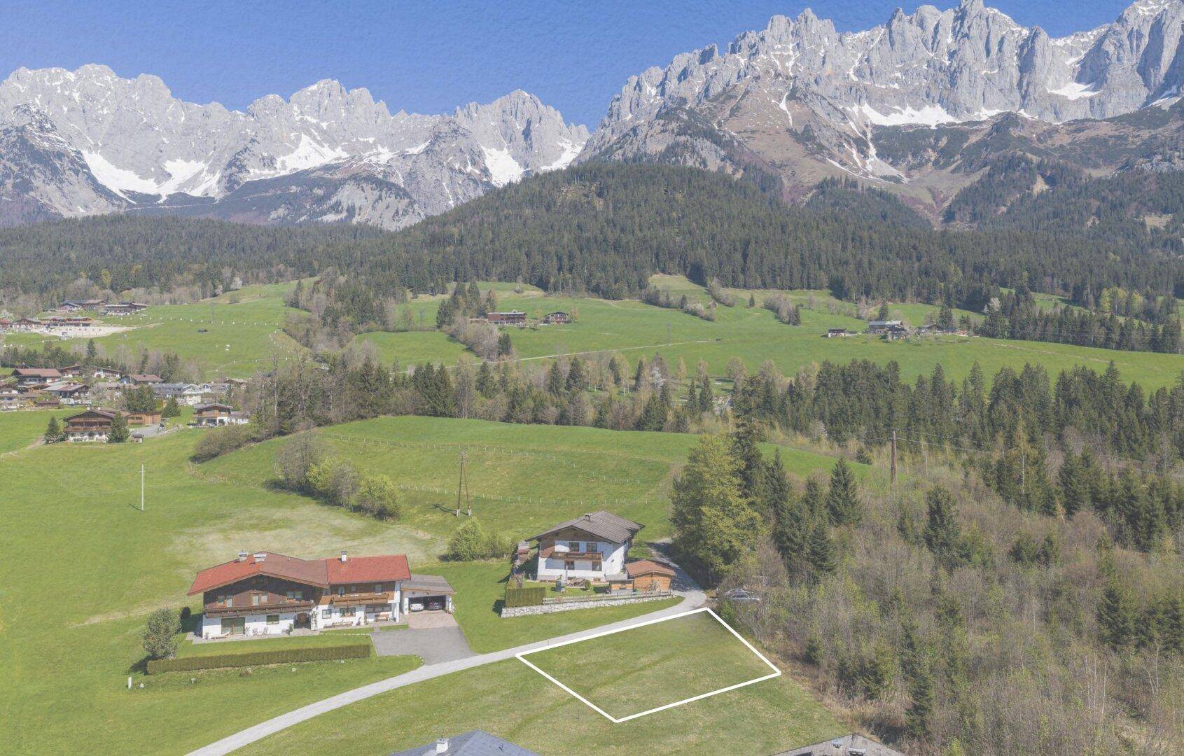 Weitläufige Luftaufnahme eines Grundstücks mit umliegenden Häusern und beeindruckendem Bergpanorama.