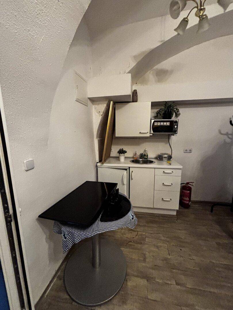 Raum mit kleiner Küchenzeile, Stehtisch und gewölbter Decke, funktional eingerichtet.