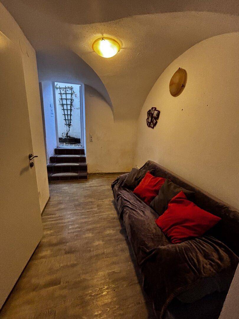 Wohnbereich mit Sofa und Blick auf eine Treppe, die zu einem anderen Bereich führt.