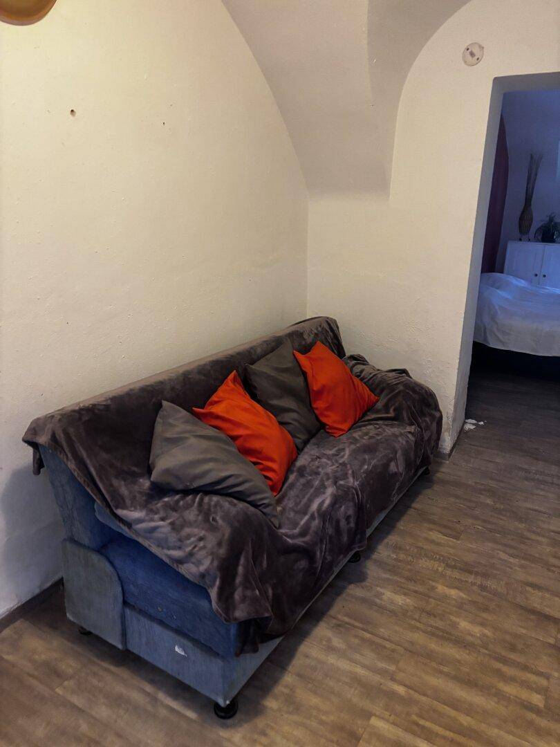 Wohnbereich mit einem bequemen Sofa und roten Kissen unter der gewölbten Decke.