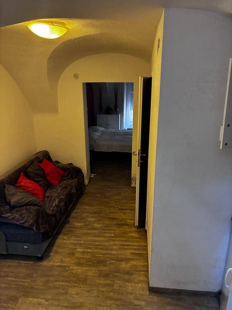 Wohnbereich mit Sofa, der zu einem Schlafzimmer führt, unter einer gewölbten Decke.