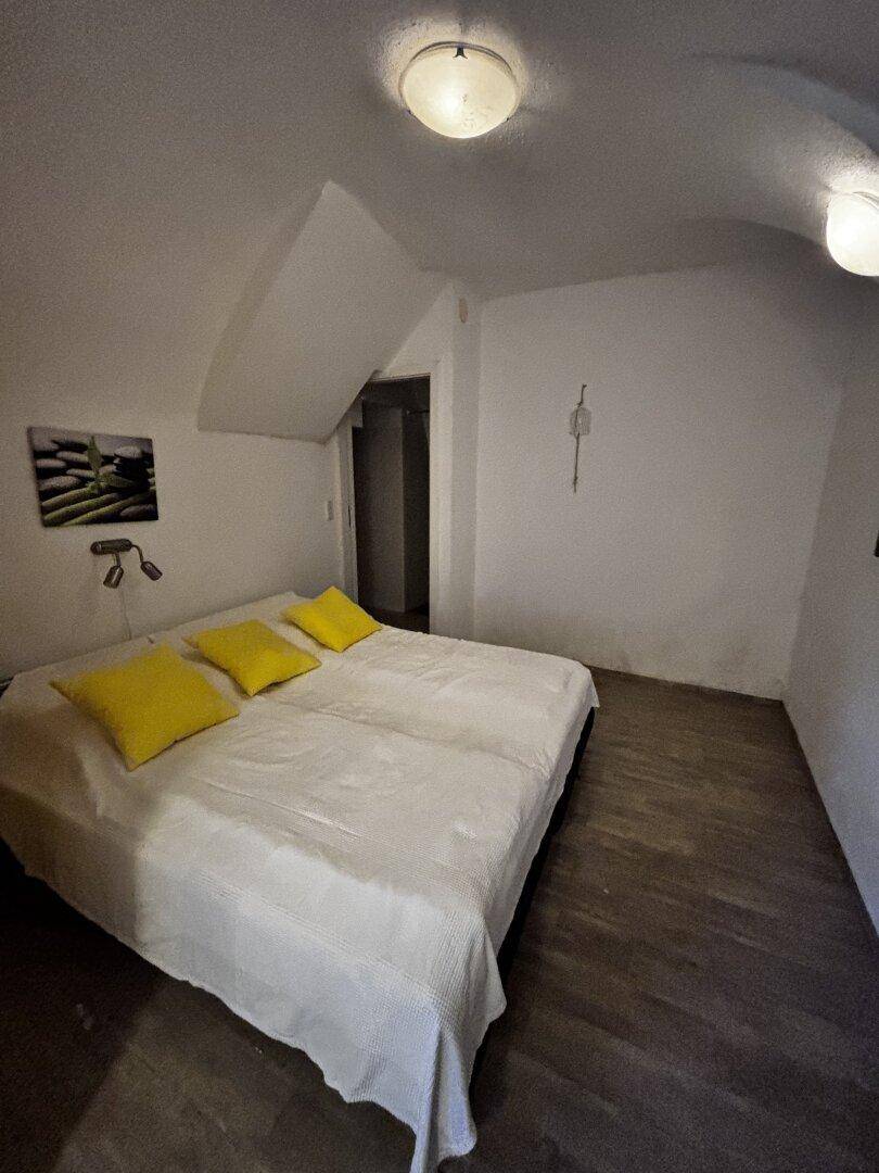 Schlafzimmer mit Doppelbett und gelben Kissen unter einem gewölbten Dach.