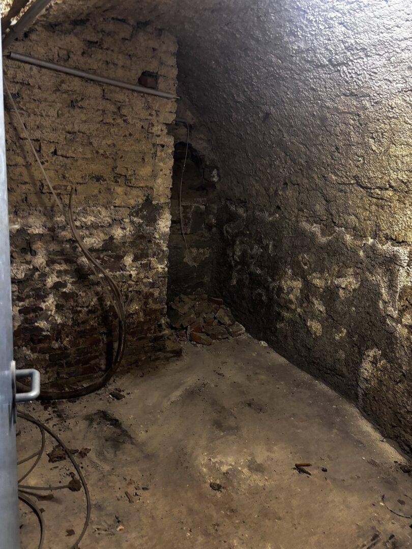 Gewölbter Kellerraum mit rauen Wänden und freiliegendem Mauerwerk.