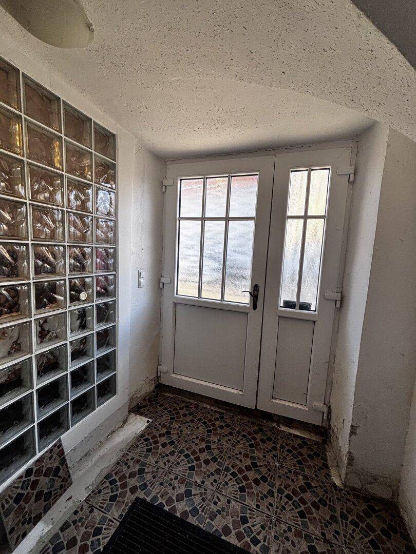 Eingangsbereich mit Glasbausteinwand, gemustertem Fliesenboden und weißen Doppeltüren.