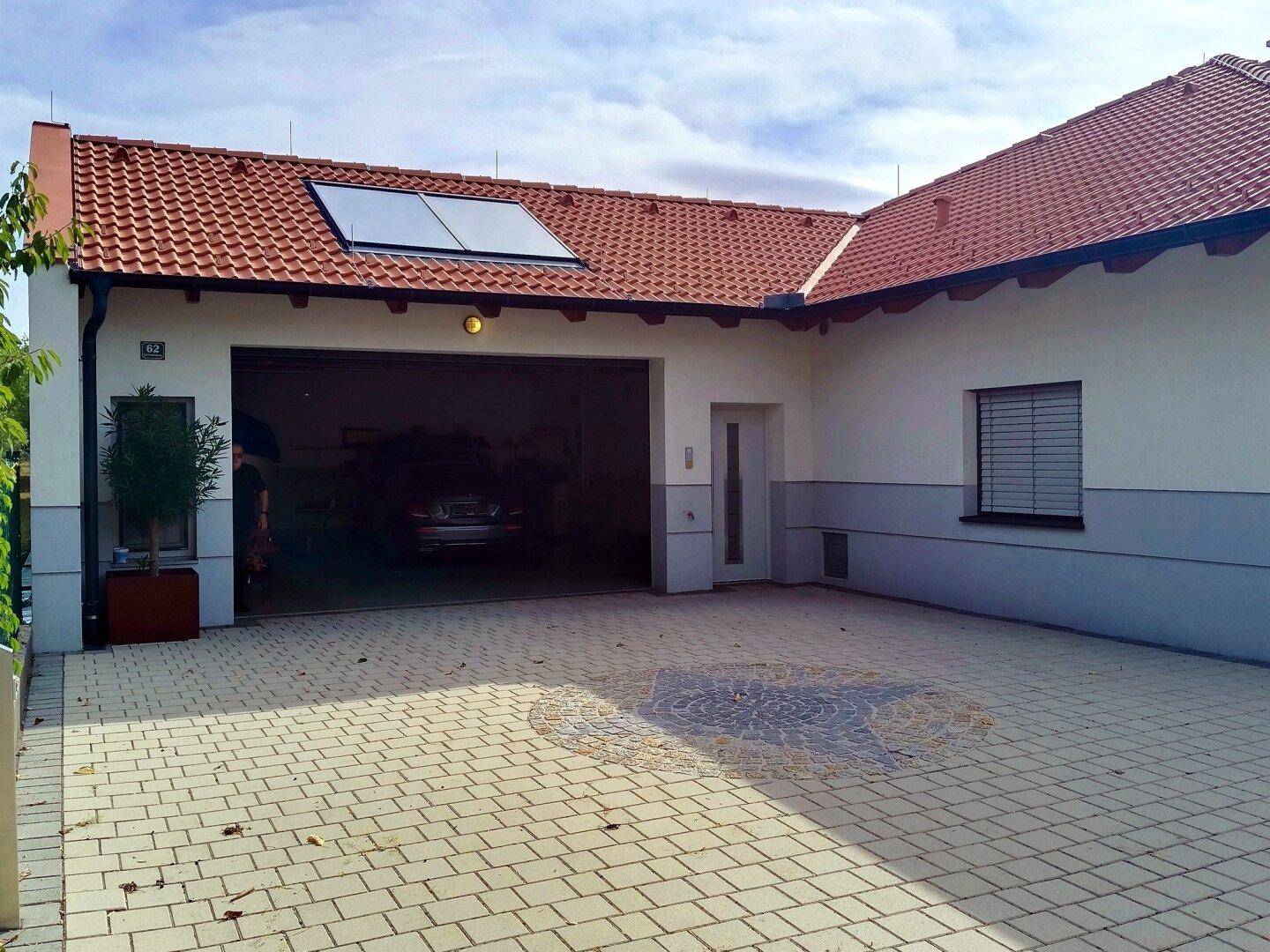 Einfahrt zur Doppelgarage mit Pflastersteinen und einem dekorativen Mosaik im Boden.