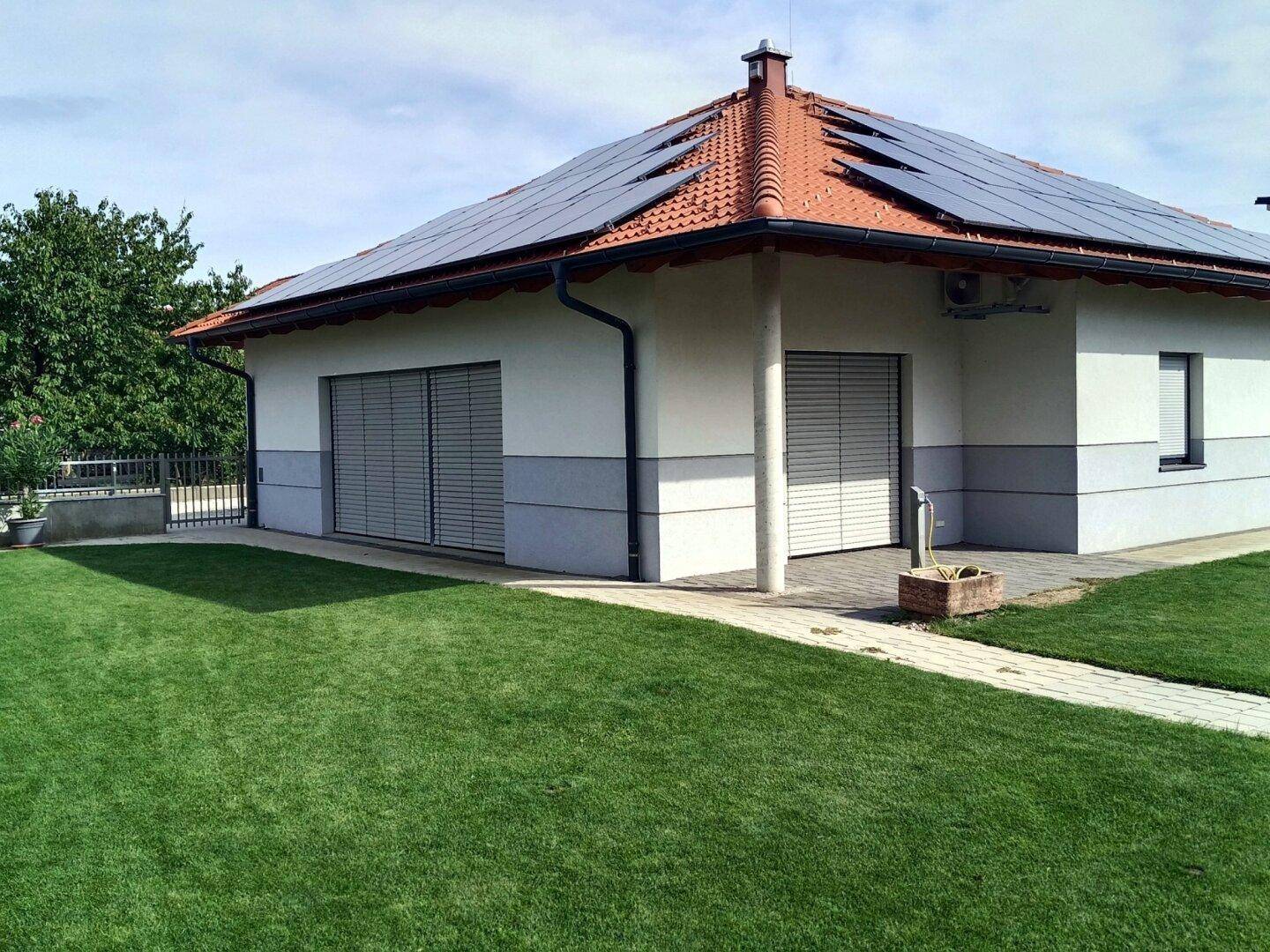 Seitenansicht des Hauses mit gepflegtem Rasen und Photovoltaikanlage auf dem Dach.