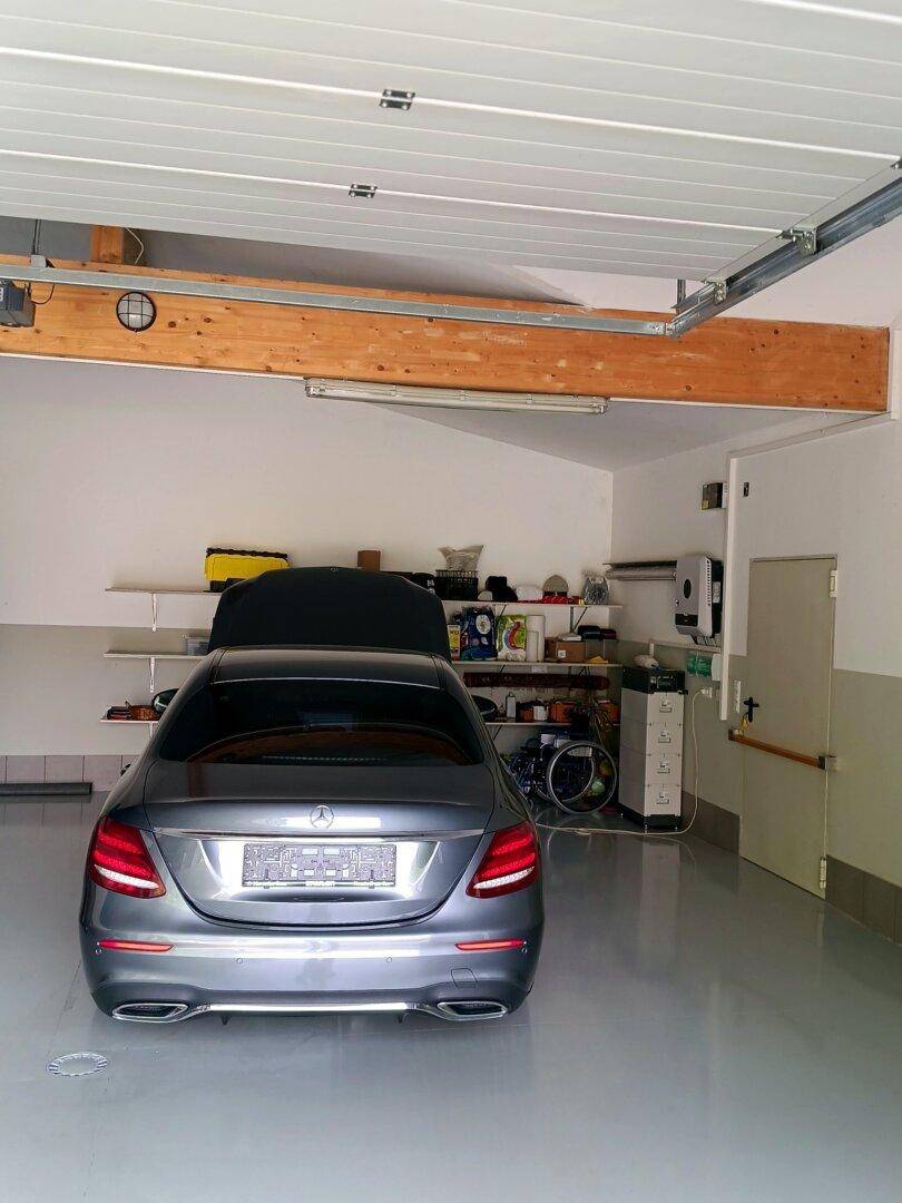 Geräumige Garage mit einem geparkten Auto und Regalen für Lagerung.