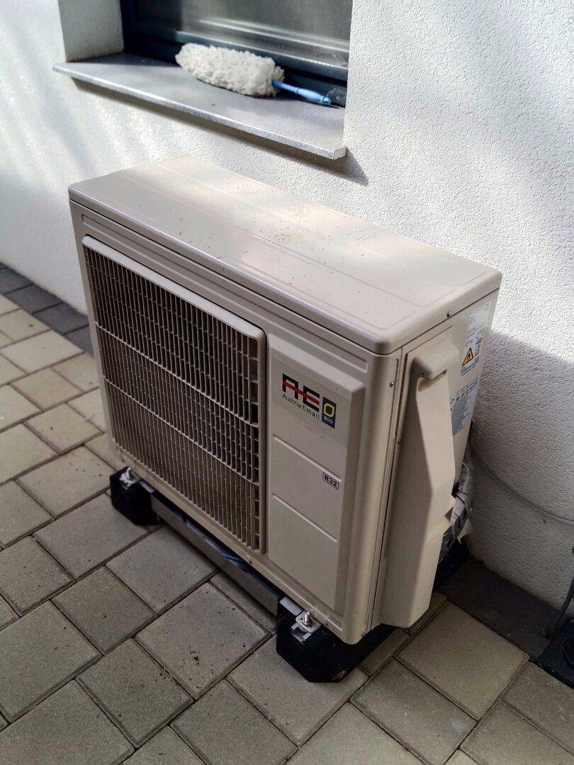Außeneinheit einer Klimaanlage oder Wärmepumpe auf gepflastertem Untergrund.