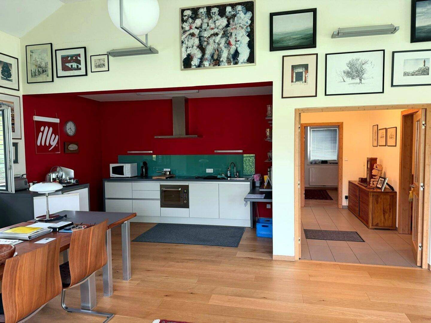 Moderne Küche in Rot und Weiß mit integrierten Geräten und Holzboden.