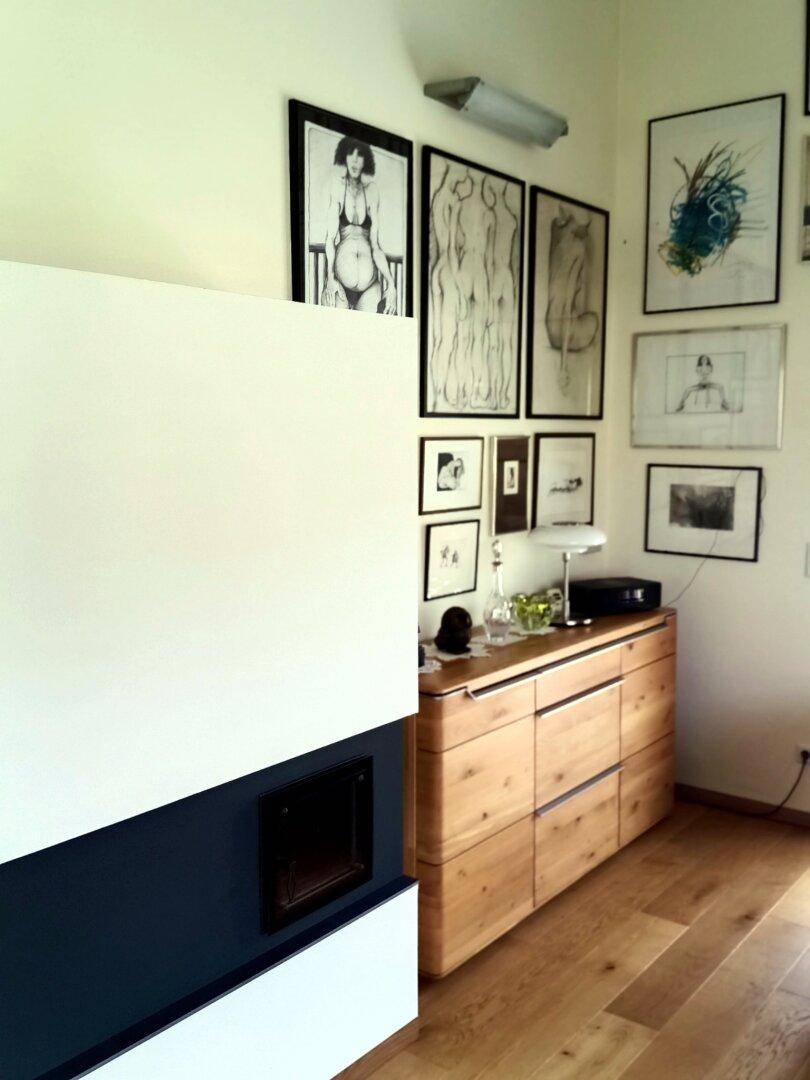Ecke im Wohnzimmer mit modernem Kamin und einem Holzschrank unter Kunstwerken.