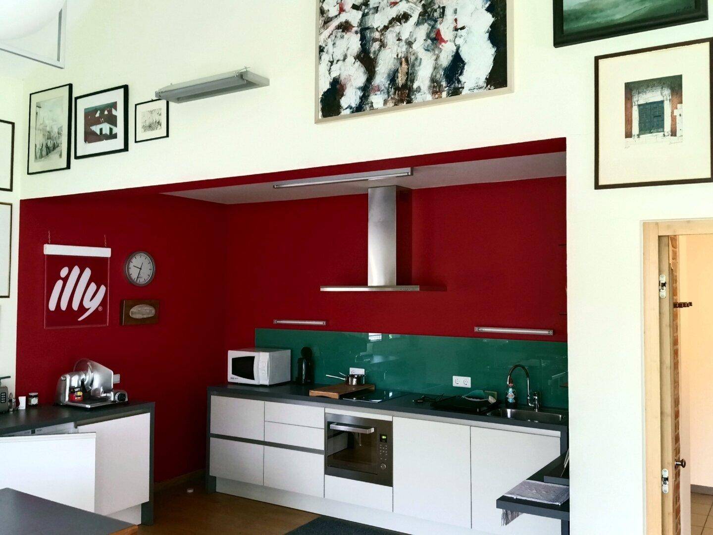 Moderne Einbauküche mit roten Wänden, Dunstabzugshaube und Mikrowelle.
