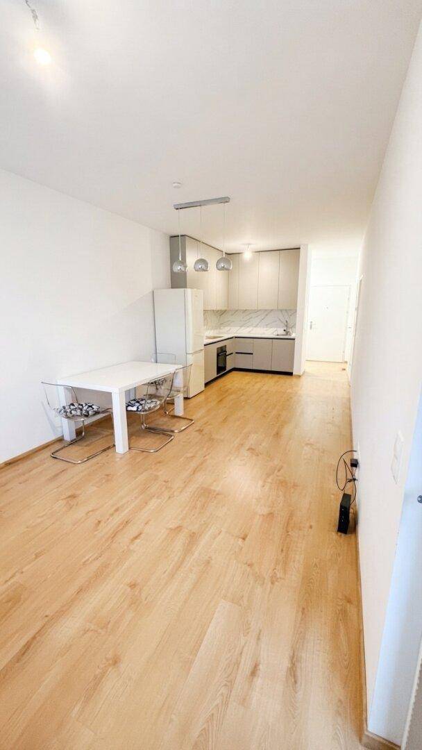 Moderner offener Wohnbereich mit integrierter Küche, Essplatz und hellem Holzboden.