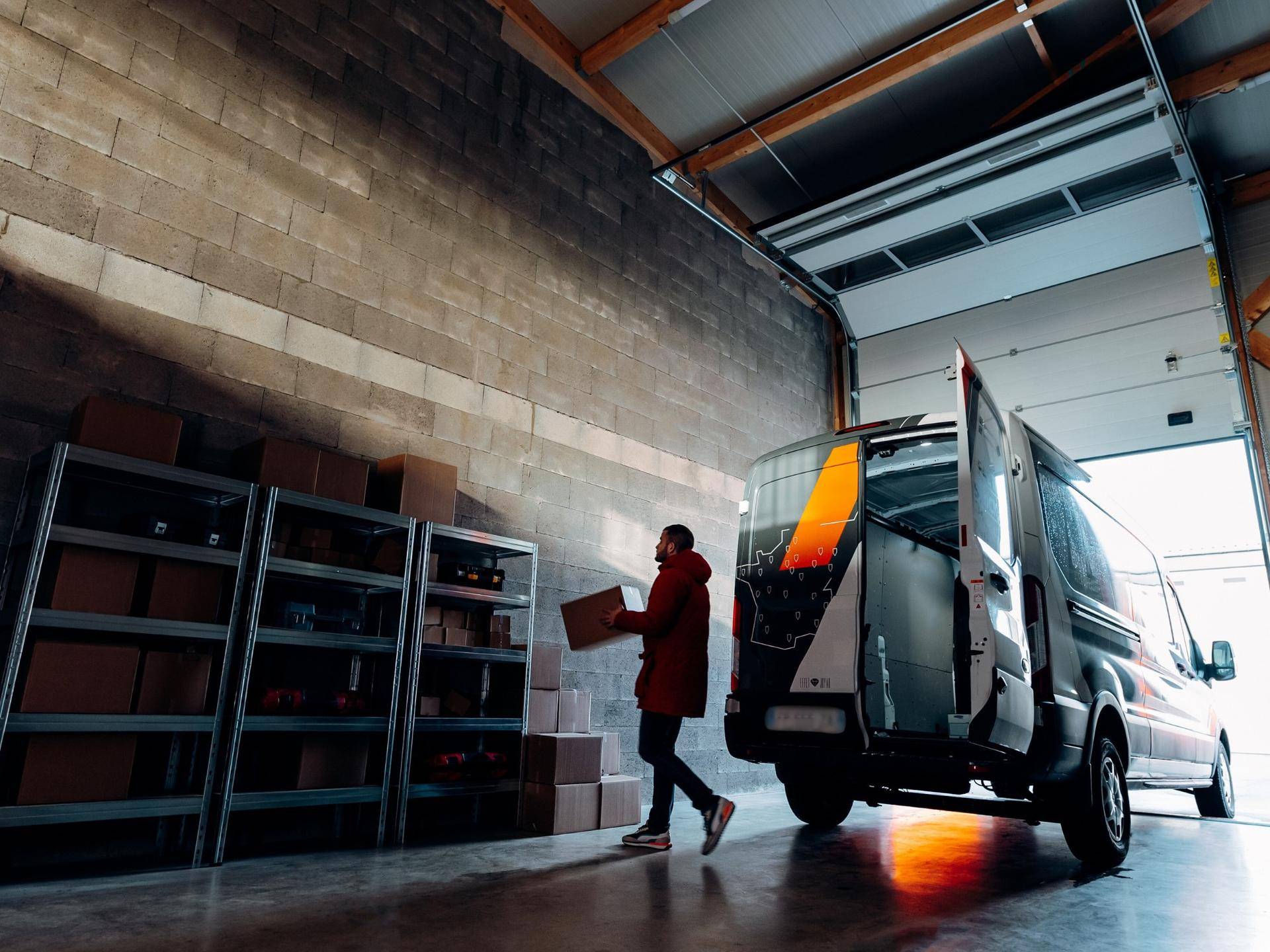 Geräumiger Lagerraum mit Betonwänden, Betonboden und einem Lieferwagen, der gerade beladen wird.