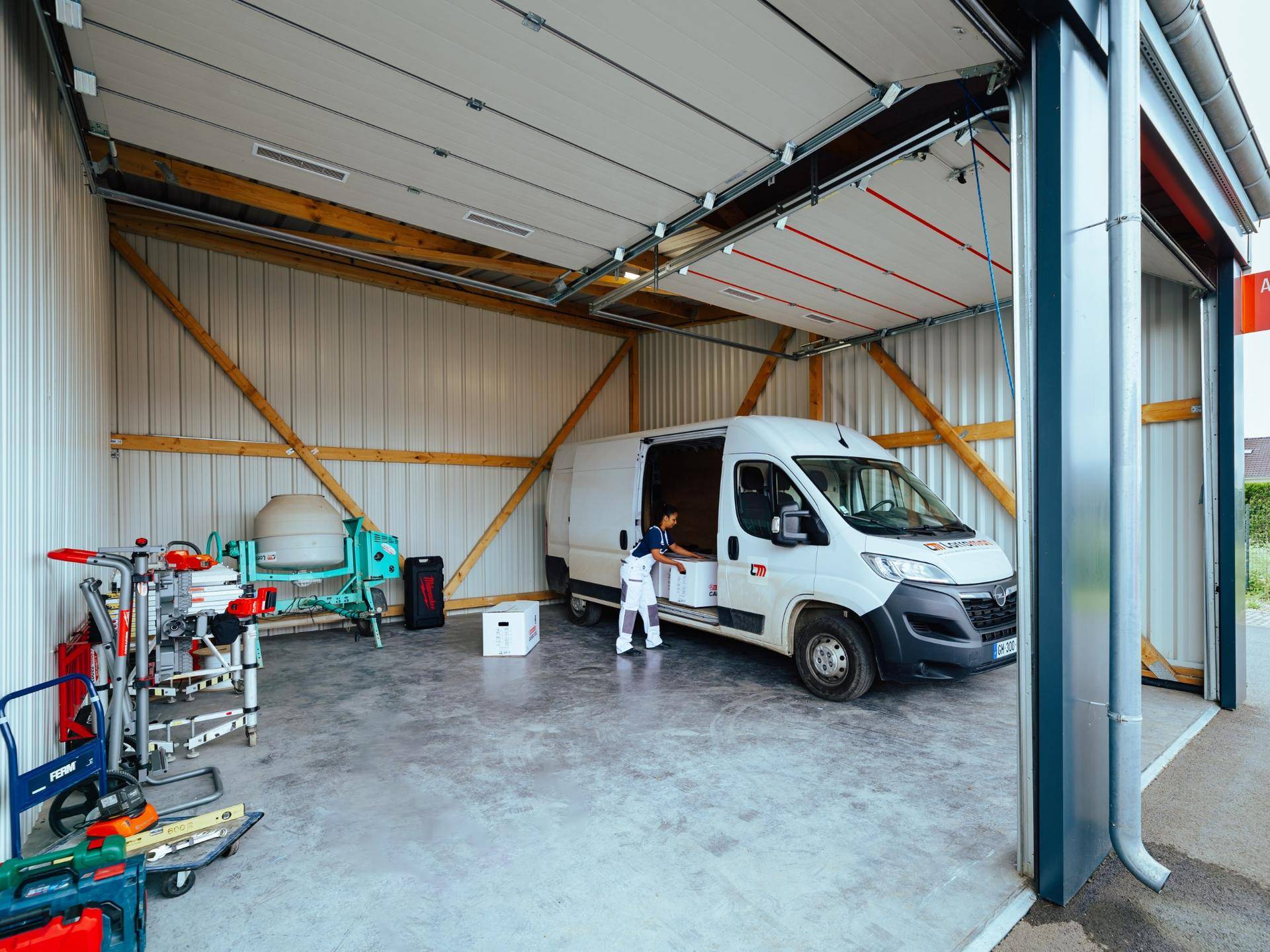 Geräumige Lagerhalle mit einem weißen Lieferwagen, Werkzeugen und Ausrüstung unter einem Holzdach.