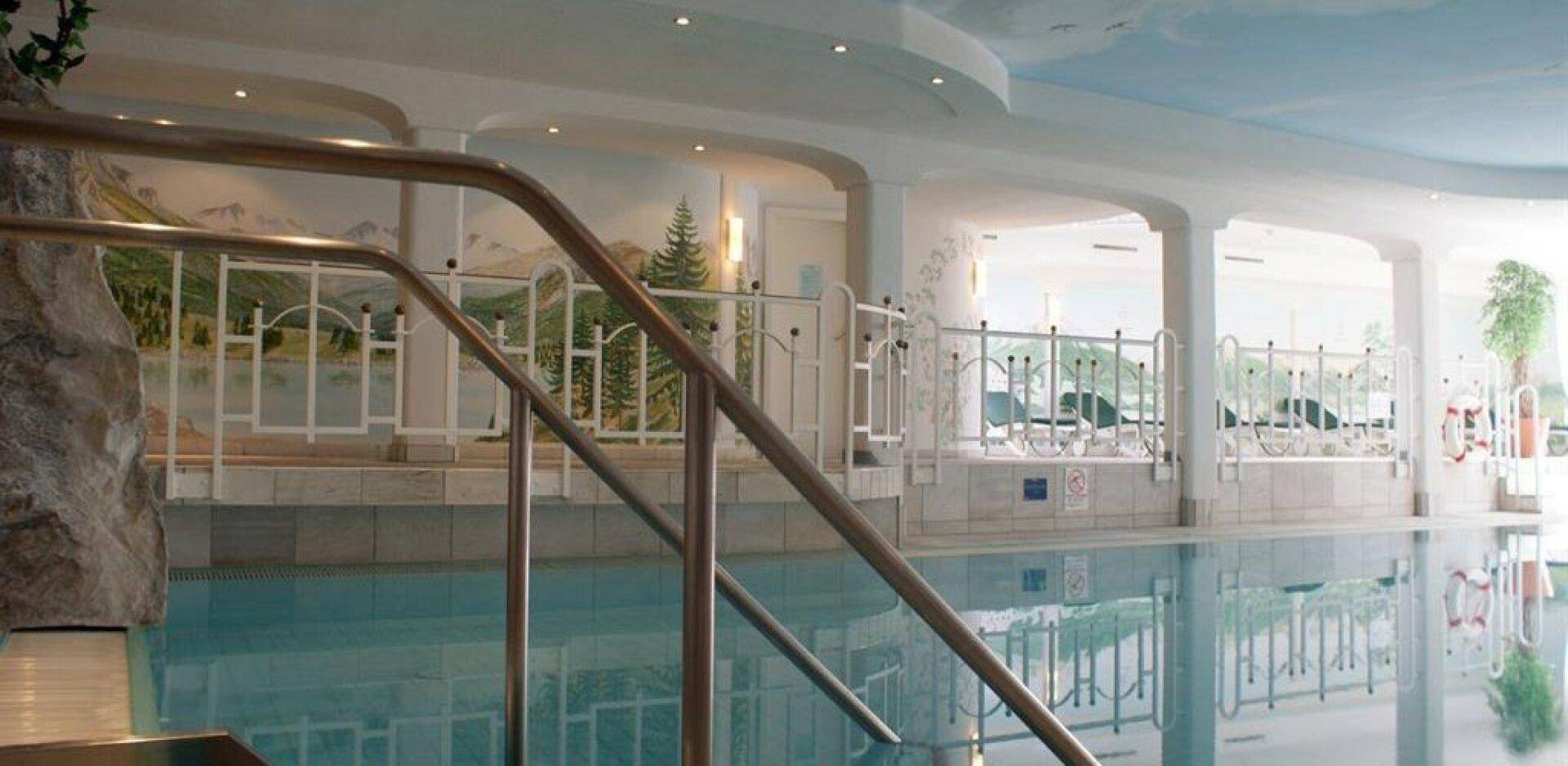Großzügiger Innenpoolbereich mit Wandmalereien, die eine Berglandschaft darstellen, und bequemen Einstiegstreppen.