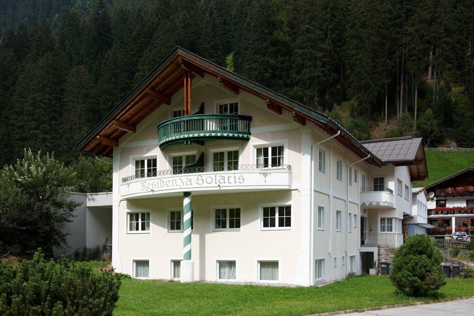 Charmantes Gebäude mit traditioneller Architektur, Balkon und umgebender grüner Landschaft.