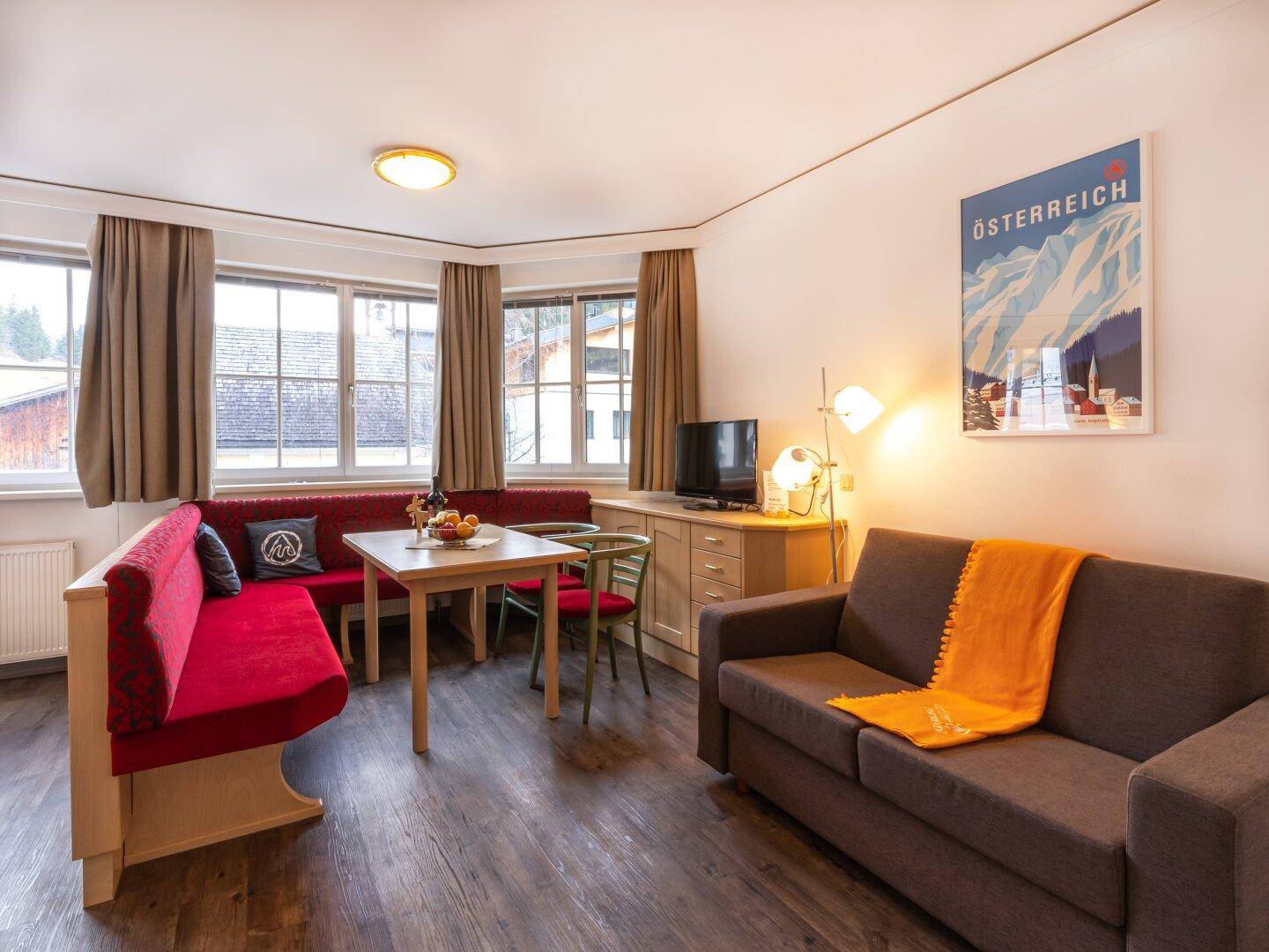 Heller Wohnbereich mit Sofa, Essecke und Fernseher, ausgestattet mit modernem Laminatboden.