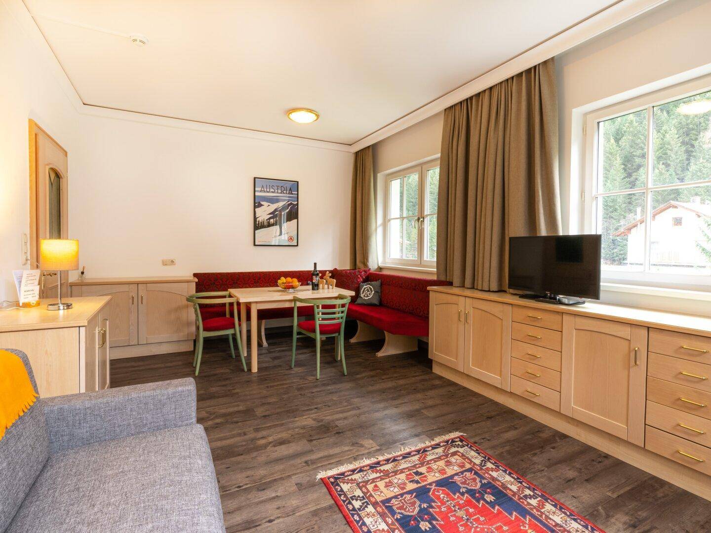 Geräumiger Wohnbereich mit Essecke, Sofa und Stauraum, ergänzt durch einen Teppich.