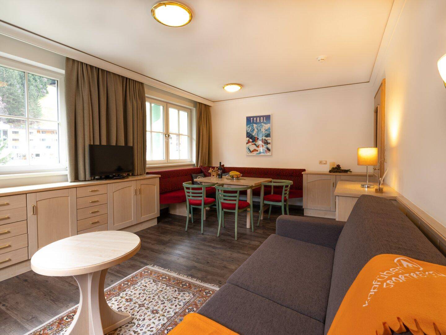 Heller Wohnbereich mit Essecke, Sofa und Couchtisch, dekoriert mit einem traditionellen Teppich.
