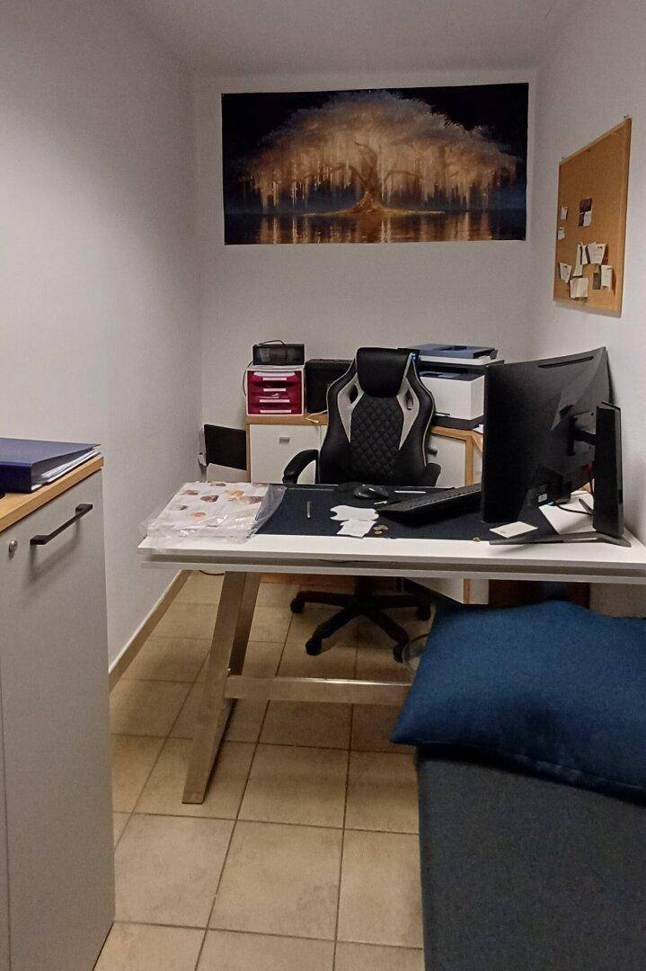 Kleines Büro mit Schreibtisch, Bürostuhl und Wanddekoration.