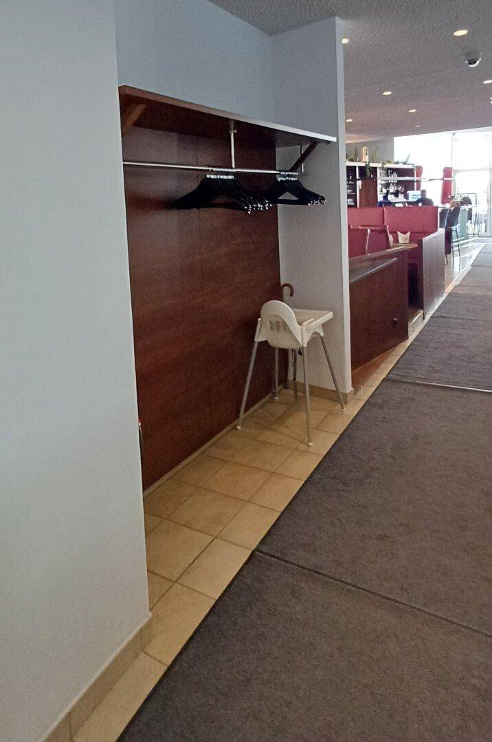 Eingangsbereich mit Garderobe, Fliesenboden und einem Kinderhochstuhl.
