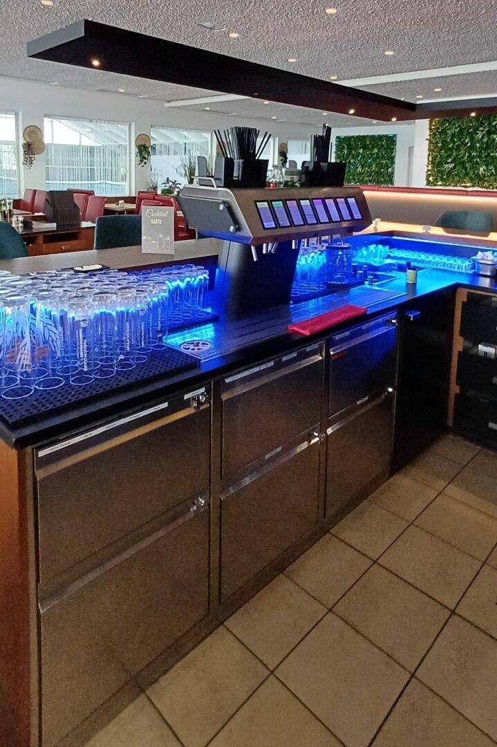 Professionelle Bar mit Edelstahlfronten, blauer Beleuchtung und Zapfanlage.