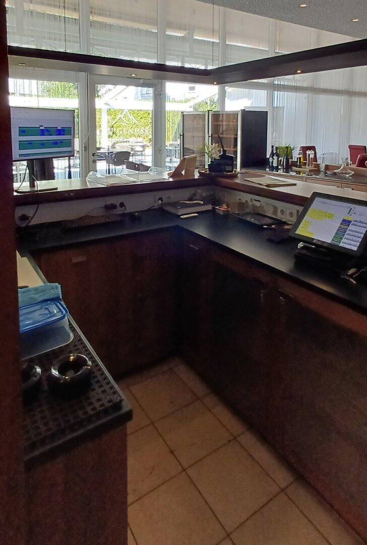 Thekenbereich einer Bar mit Kassensystemen und Blick auf den Außenbereich.