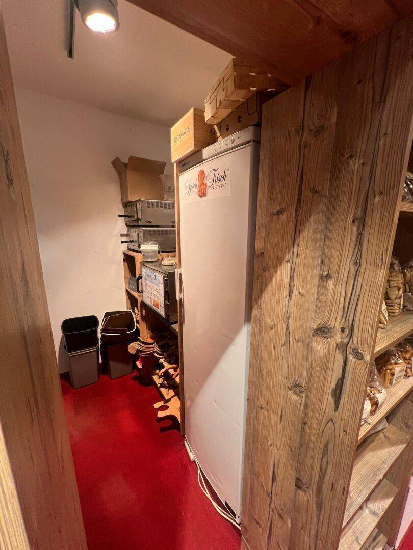Lagerbereich mit einem Kühlschrank und weiteren Regalen, die für die Aufbewahrung von Waren genutzt werden.