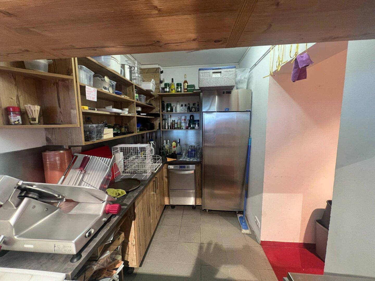 Gewerbliche Küche mit Arbeitsflächen, Spülmaschine und großem Kühlschrank, ideal für Gastronomiebetriebe.