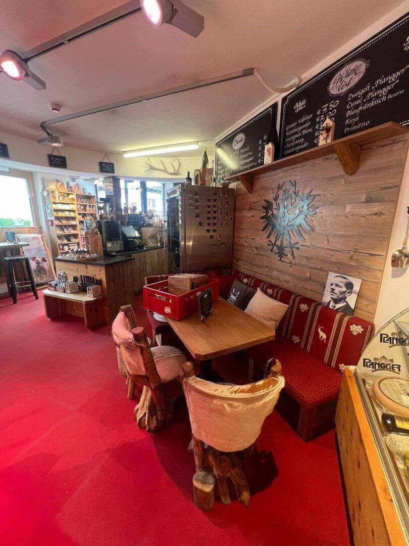 Rustikaler Sitzbereich in einem Bistro mit Eckbank, Holztisch und Stühlen, auf rotem Teppichboden.
