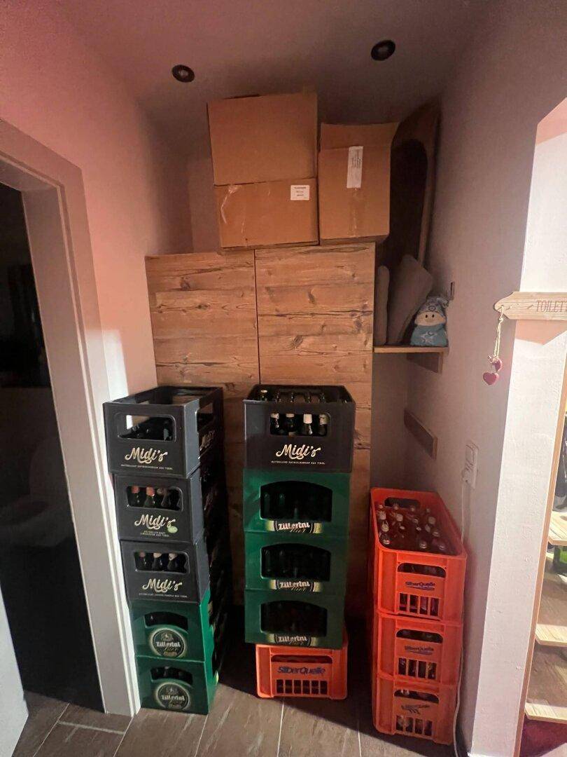Lagerbereich mit gestapelten Getränkekisten und Holzverkleidung an der Wand, für Vorräte genutzt.