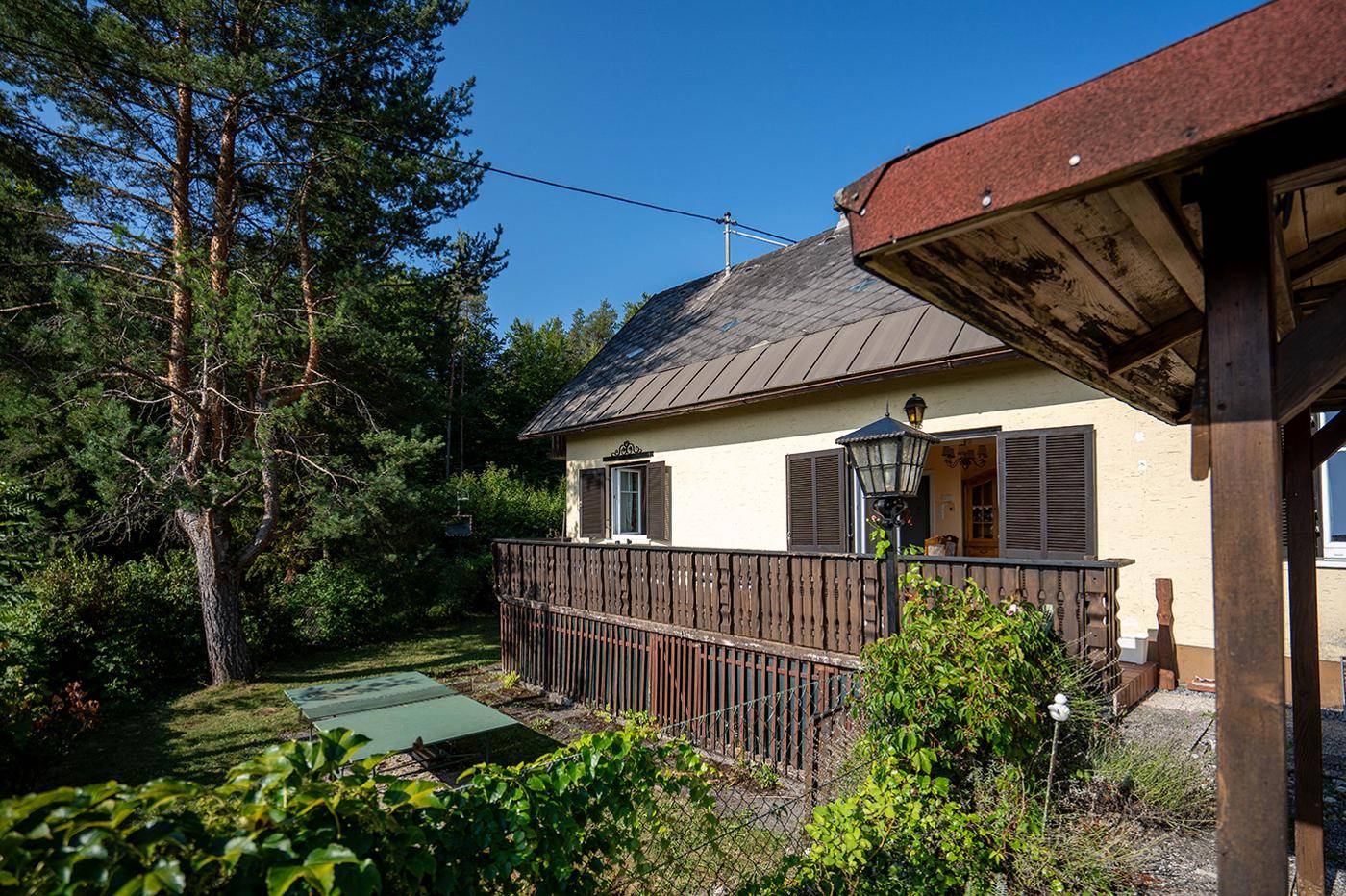 Charmantes Haus mit Balkon, umgeben von viel Grün und einem idyllischen Pavillon im Garten.