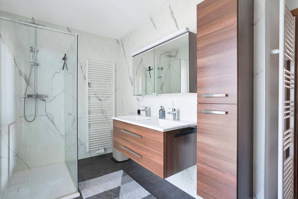 Modernes Badezimmer mit begehbarer Dusche, Doppelwaschbecken und Marmoroptik-Fliesen.