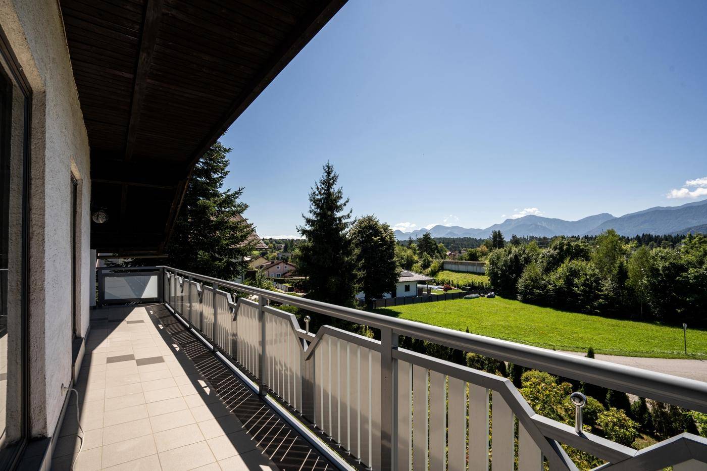 Langer Balkon mit Fliesenboden und weitem Blick über die grüne Landschaft.
