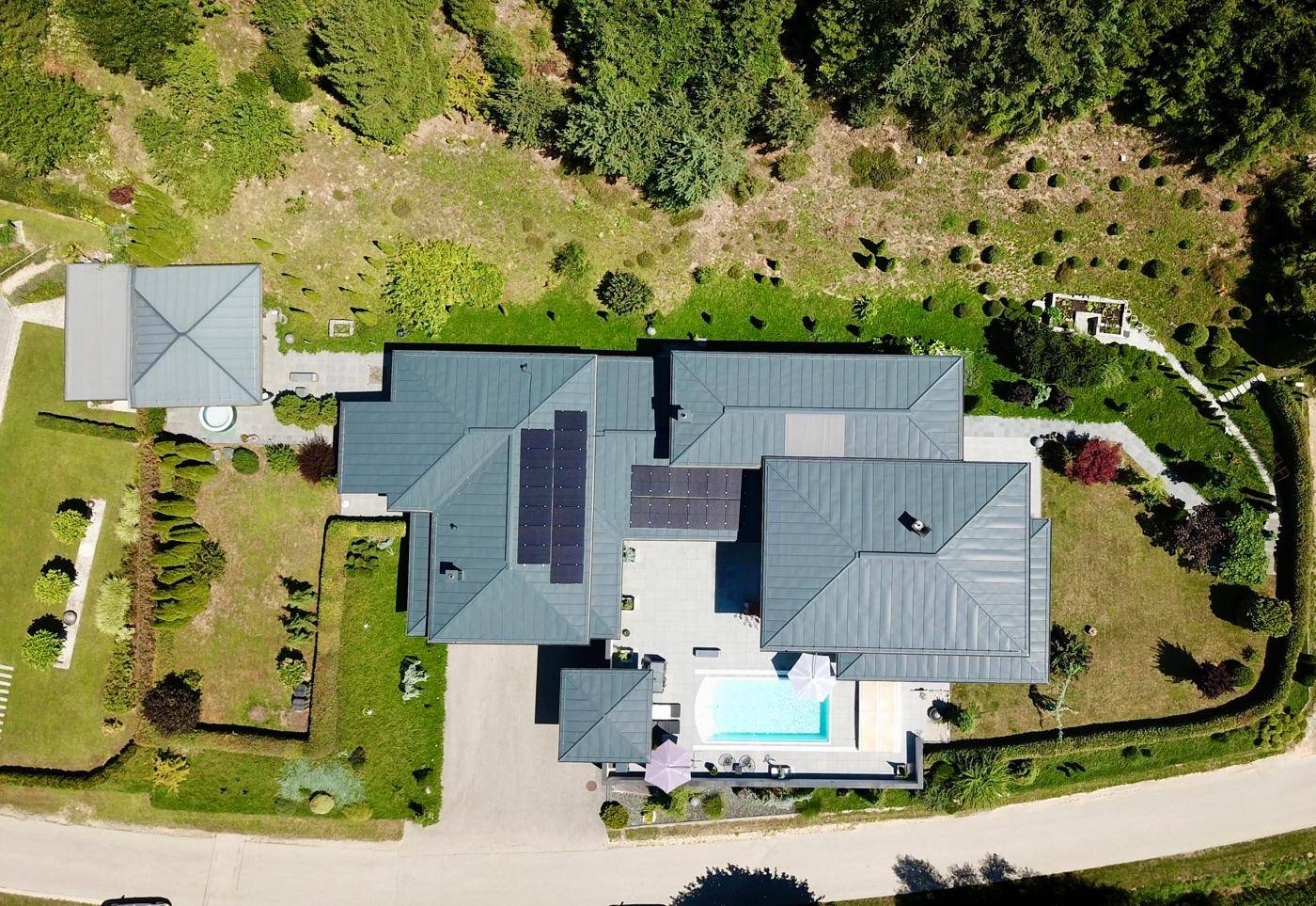 Luftaufnahme des Anwesens mit modernem Haus, Pool und weitläufigem Gartenbereich.