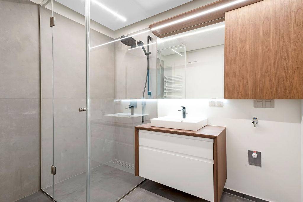 Detaillierte Ansicht der begehbaren Dusche mit Regenduschkopf und modernem Waschtisch im Badezimmer.