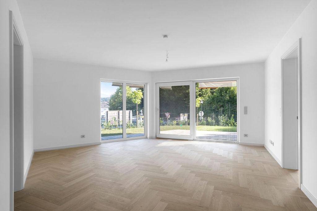 Heller Wohnraum mit Fischgrätparkett und großen Schiebetüren zum Gartenbereich.