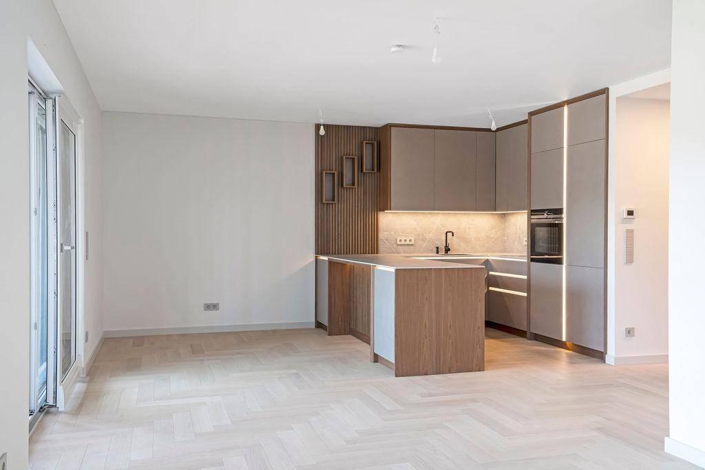 Moderne offene Küche mit grauen und holzfarbenen Schränken, Kochinsel und integrierten Geräten.