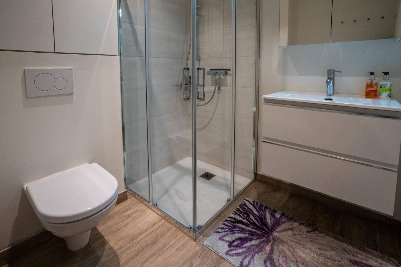 Modernes Badezimmer mit Duschkabine, wandhängendem WC und Einzelwaschbecken.