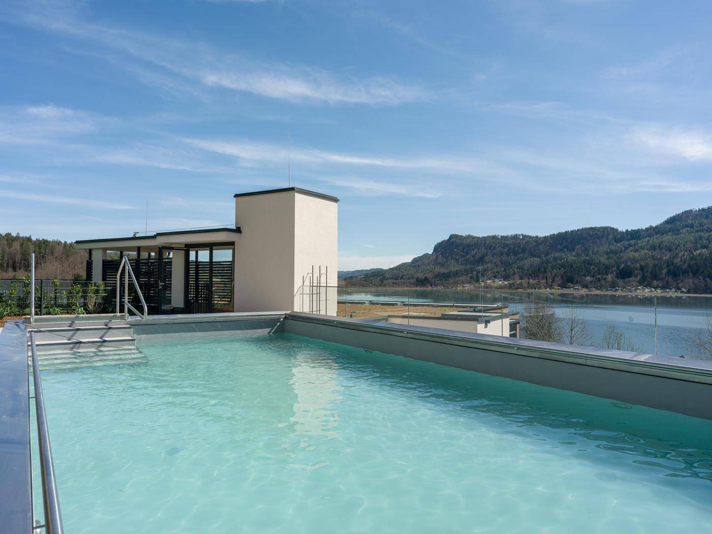 Dachterrasse mit Infinity-Pool und atemberaubendem Blick auf den See und die umliegende Berglandschaft.